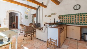 Una cocina rústica con vigas de madera a la vista, un arco de piedra y un salpicadero de azulejos.