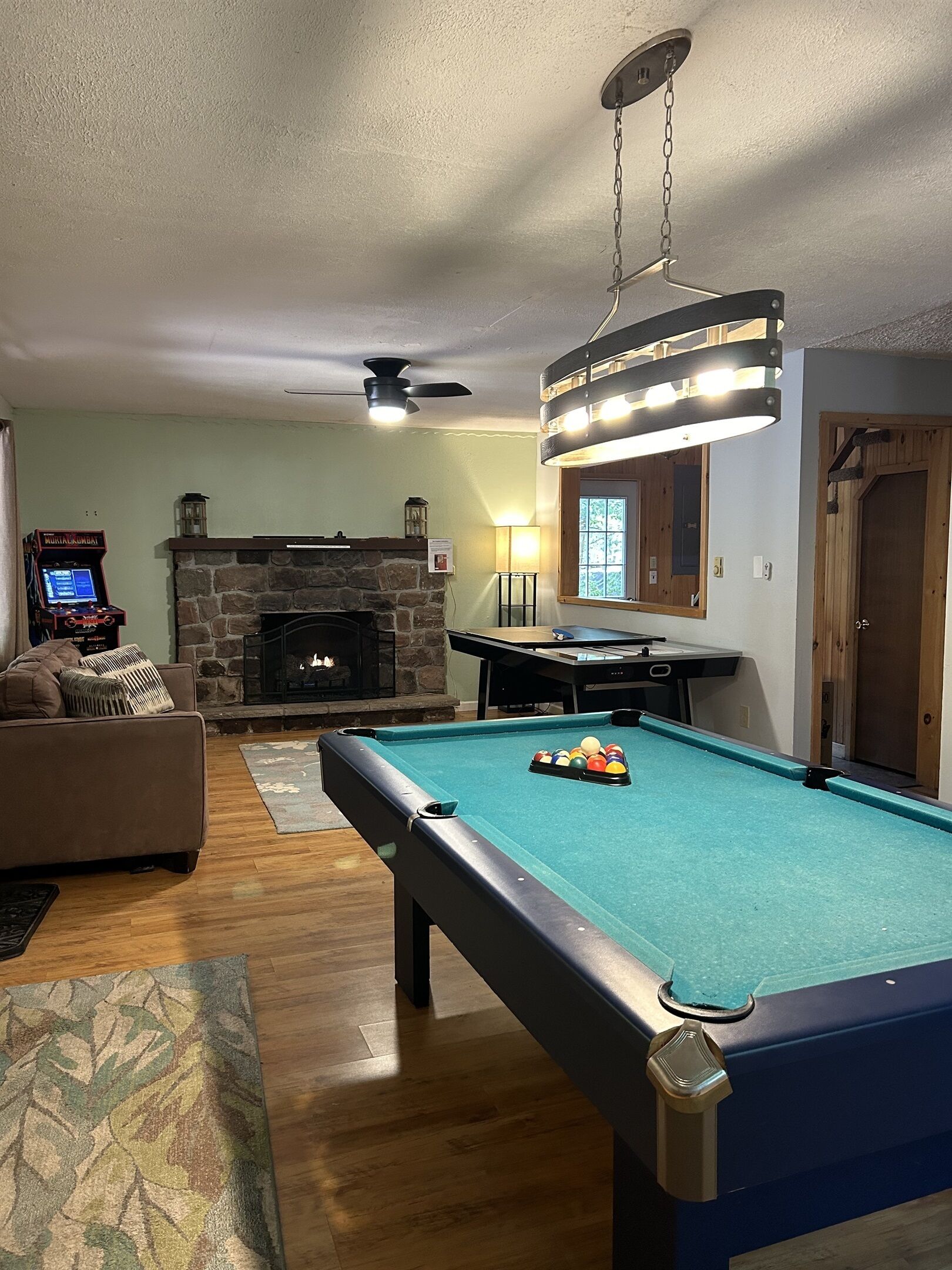 A cozy living room with a pool table, a fireplace, and a television.