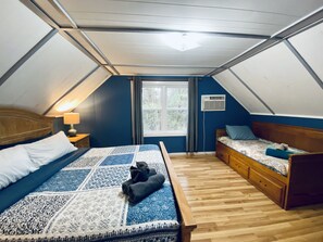 Un dormitorio con una cama de madera, una cama más pequeña, una ventana y un ventilador de techo.