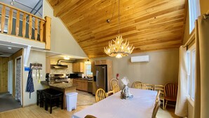 Un comedor amplio con una larga mesa, sillas de madera y un candelabro.
