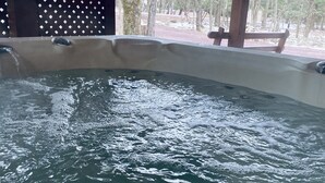 Tinaco con burbujas, rodeado por una terraza de madera y árboles.