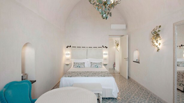 A bedroom with a bed, a chair, a bench, a chandelier, and a mirror. - Holiday Home 'Dimora Elegante In Costa D'Amalfi' with Sea View, Wi-Fi and Air Conditioning (Conca dei Marini)