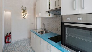 A kitchen with white cabinets, a blue countertop, a stainless steel sink, a black oven, and a wall-mounted light fixture. - Holiday Home 'Dimora Elegante In Costa D'Amalfi' with Sea View, Wi-Fi and Air Conditioning (Conca dei Marini)