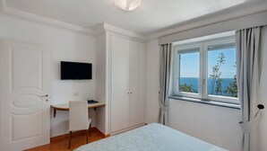 Un dormitorio con cama, escritorio, silla, televisión y ventana con vista.