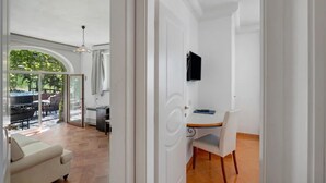 Un espacio de sala-comedor abierto con sofá, mesa de comedor con sillas, televisor montado en la pared y puerta corrediza de vidrio que da a un patio exterior.