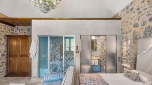 A bedroom with a bed, a bench, a wardrobe, and a bathroom with a mirror and sink.