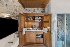 Una cocina compacta con armarios de madera, un lavamanos integrado y un televisor.