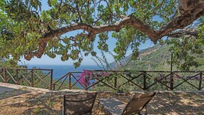 An outdoor seating area with chairs, a wooden fence, and a view of the sea.