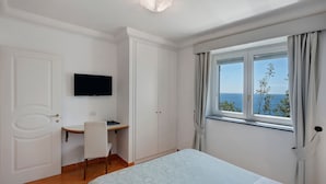 Une chambre à coucher comprenant un lit, un bureau, une chaise, un téléviseur et une fenêtre donnant sur un beau paysage.