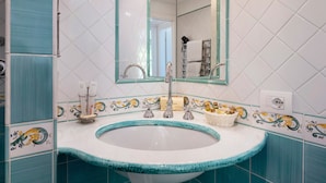 Une salle de bain avec un lavabo, un miroir et des carreaux décoratifs.