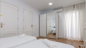 Ein Hotelzimmer mit zwei Betten, einem Schrank, einem Spiegel und einer Klimaanlage.