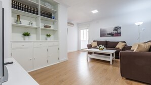 Ein modernes Wohnzimmer mit einem weißen Schrank, einem braunen Sofa, einem weißen Couchtisch und einem Gemälde an der Wand.