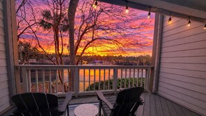 Une véranda abritée, avec deux chaises et une petite table, d’où l’on peut admirer le coucher de soleil sur une étendue d’eau.
