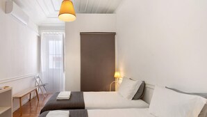 Habitació d'hotel amb dos llits, una panxa, un escriptori i una finestra amb cortines.
