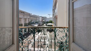 Vista des d'un balcó amb barana de ferro forjat, amb una perspectiva d'un carrer ple d'edificis i un cel blau clar.