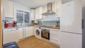 Una cocina moderna con armarios blancos, lavavajillas, lavadora, horno y refrigerador Samsung.