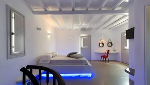 A modern bedroom with a bed, a chair, a TV, and a ceiling with exposed beams. - Apartment at 'Echinousa Kimolos Maisonette no3' Hotel with Sea View, Wi-Fi, and Air Conditioning (Psathi)
