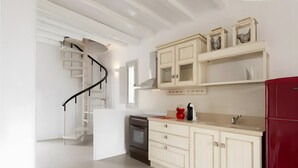 A kitchen with a built-in oven, a red refrigerator, and a white staircase. - Apartment at 'Echinousa Kimolos Maisonette no3' Hotel with Sea View, Wi-Fi, and Air Conditioning (Psathi)