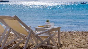Ein Strandstuhl und ein Tisch mit Blick auf das Meer und einen fernen Berg.