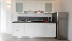 Eine moderne Küche mit weißen Schränken, einem Edelstahlkühlschrank und einer schwarzen Arbeitsplatte.