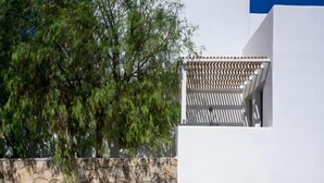 En modern byggnad med en stenvägg, en vit fasad och en träpergola.