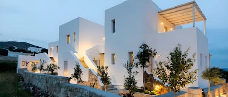 A modern white building with a stone retaining wall, a staircase, and potted plants.