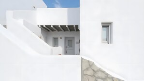 A white building with a stone wall, a door, and a window.