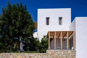 A modern building with a stone wall, a wooden pergola, and a clear blue sky.