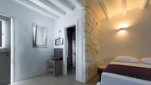 A modern bedroom with a bed, a nightstand, a wall-mounted light, and a stone accent wall.