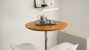 A round wooden table with a tray holding a teapot and two cups, flanked by two white chairs with wooden legs. - Mediterranean Escape Between the Sea and the Esterel Mountains (Théoule sur Mer)