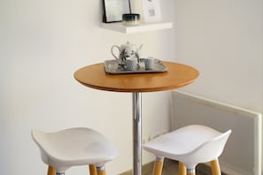 A round wooden table with a tray holding a teapot and two cups, flanked by two white chairs with wooden legs. - Mediterranean Escape Between the Sea and the Esterel Mountains (Théoule sur Mer)