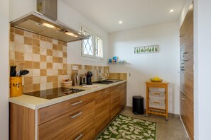 A modern kitchen with a checkered backsplash, wooden cabinets, a stainless steel range hood, and a small window. - Mediterranean Escape Between the Sea and the Esterel Mountains (Théoule sur Mer)