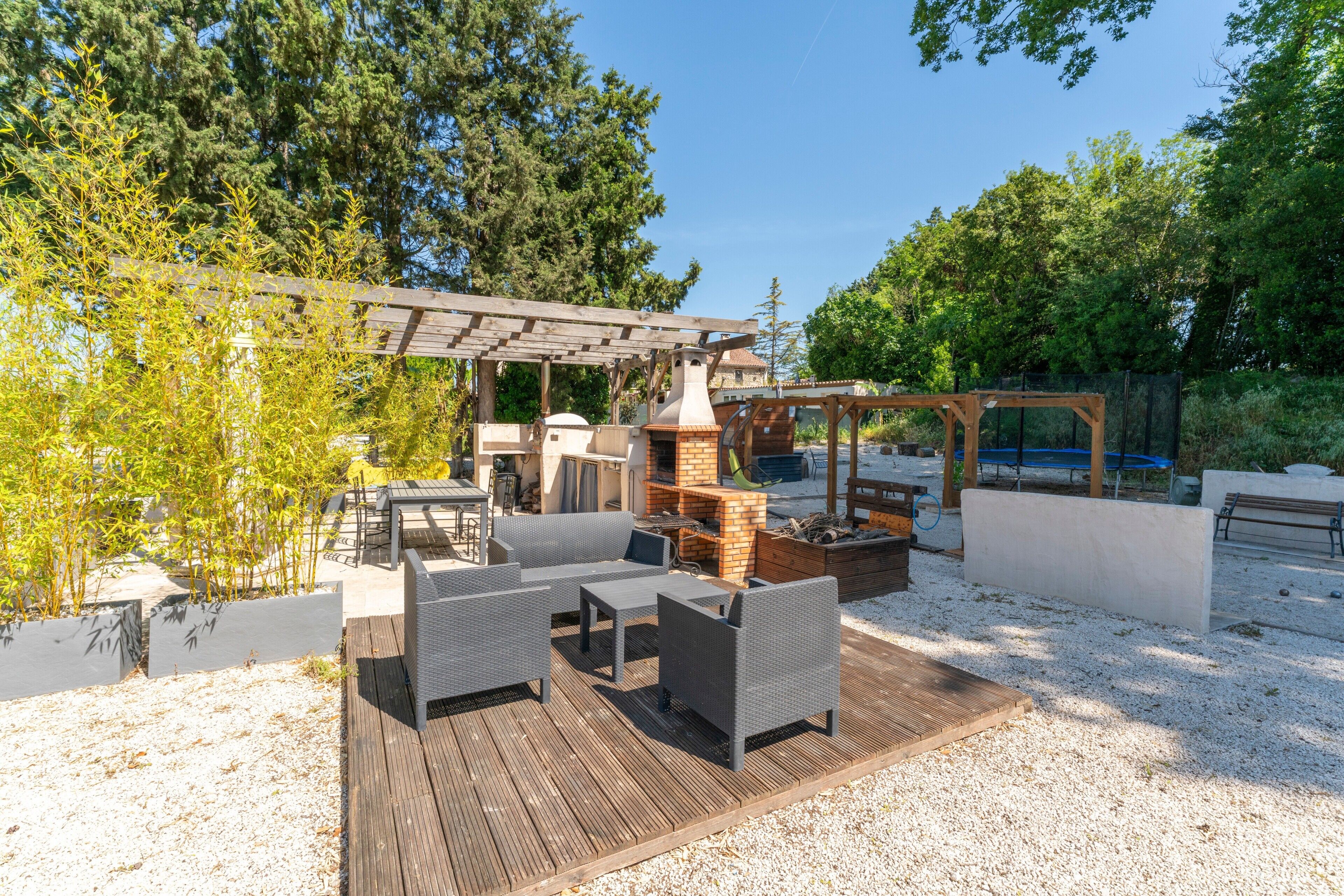 An outdoor patio with wicker furniture, a brick fireplace, and a pergola.