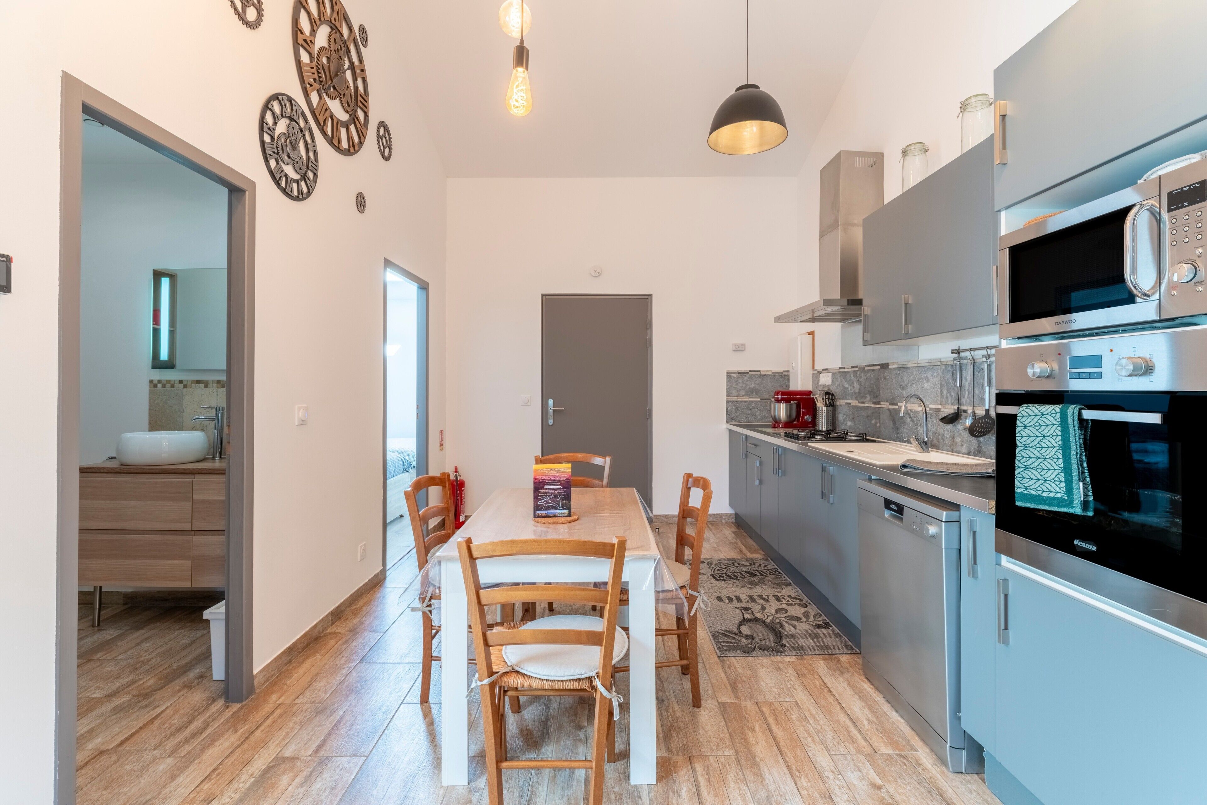 A modern kitchen with a dining table, chairs, and a microwave.