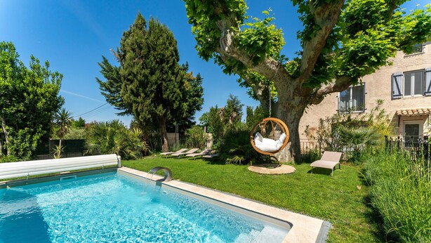 A swimming pool with a tree and lounge chairs in the background.