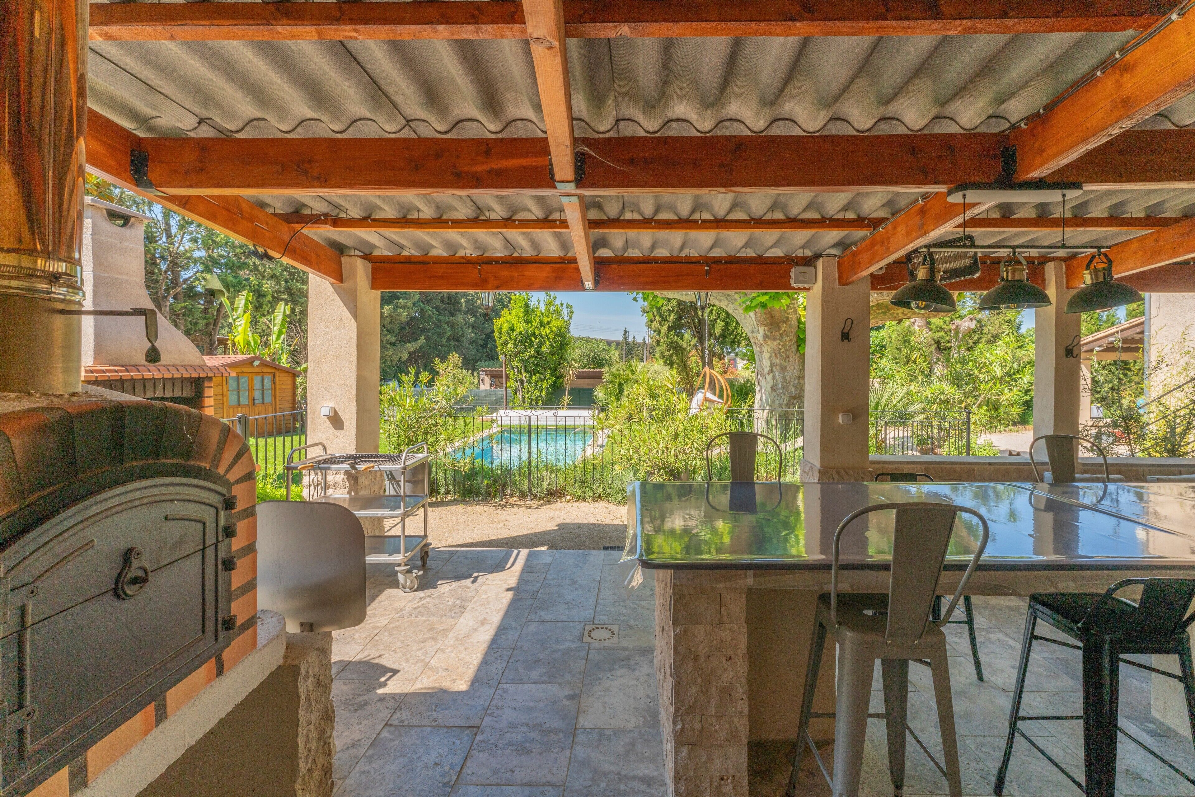 An outdoor patio with a grill, a glass table, and chairs.