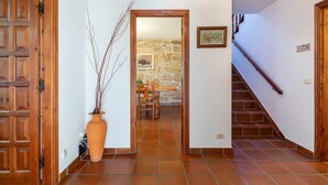 A hallway with a wooden door, a potted plant, a stone wall, a dining table with chairs, and a staircase. - Bed and Breakfast 'Habitación Triple 1' with Mountain View, Shared Pool and Wi-Fi (Tui)