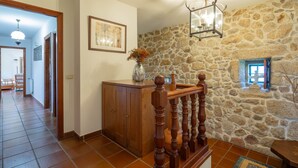 Ein Flur mit Steinwand, Holzwand, gefliestem Boden und einer Vase mit Blumen.