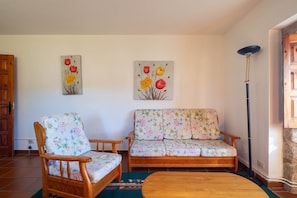 En stue med en træsofa, en trælænestol og to blomsterbilleder på væggen.