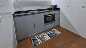 Une cuisine moderne avec des meubles gris, un four à micro-ondes en acier inoxydable, un évier et un four.