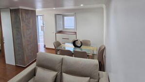 Un salon moderne avec un canapé, une table à manger et des chaises, et un coin cuisine à l’arrière-plan.