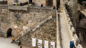Un château de pierre historique, orné d’un drapeau, doté de fenêtres en arc et entouré de douves.