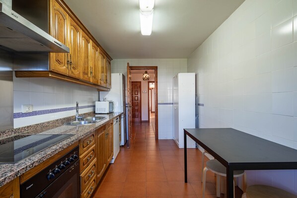A kitchen with wooden cabinets, a built-in stove, and a dining area with a table and chairs.