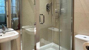 Un baño moderno con ducha de vidrio, inodoro y lavamanos.