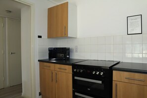 Eine Küche mit Holzausstattung, einer schwarzen Mikrowelle, einem Herd und einem an der Wand befestigten Schild.