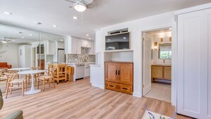 Uma sala de estar espaçosa com mesa de jantar, armários de madeira e ventilador de teto.