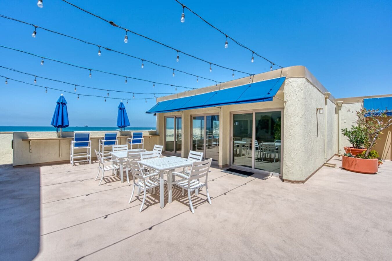 Um terraço no telhado com área de estar externa, luzes de festa e vista para a praia.
