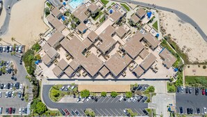 Vista aérea de um hotel com piscina central, vários andares e um estacionamento.
