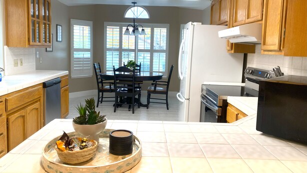 A kitchen with wooden cabinets, a dining area with a table and chairs, and a refrigerator.