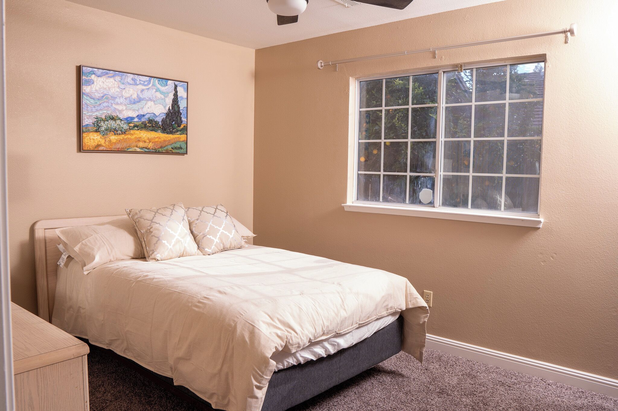 Un dormitorio con cama, ventana y un cuadro en la pared.